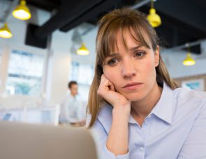 Depressed businesswoman in office behind her laptop